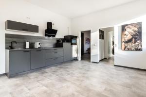 a kitchen with gray cabinets and a painting of a woman at Modernes Apartment in Mistelgau 3 in Mistelgau