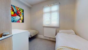 a small bedroom with two beds and a window at Stunning 2 Bed Georgian Apartment in North Walsham