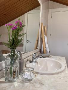 a bathroom sink with a vase with flowers in it at Turismo Casa Benito in Villanueva de Arosa +29 photos