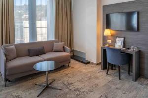 a living room with a couch and a desk with a television at Boutique Hotel Portorose in Portorož