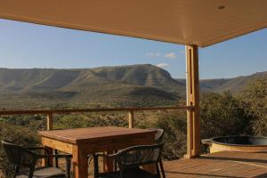 a table and chairs on a deck with a view of mountains at Valley View Escape in Uitkeer