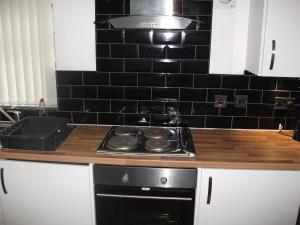 a kitchen with a stove and a black tiled wall at The Grange in Middlesbrough