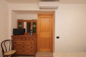 a bedroom with a wooden door and a dresser with a television at Gioeni 23 in Cefalù