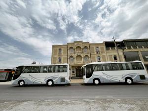 two white buses parked in front of a building at Almaz PLAZA in Tashkent