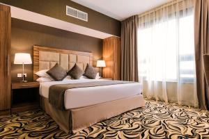 a bedroom with a large bed and a large window at Emirates Plaza Hotel in Abu Dhabi +13 photos