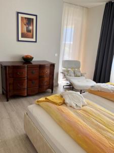 a bedroom with two beds and a dresser and a chair at Ascona: ORTO DEGLI ANGIOLI in Ascona