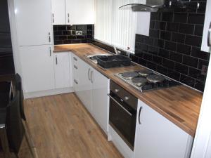 a kitchen with white cabinets and black tiles at The Grange in Middlesbrough
