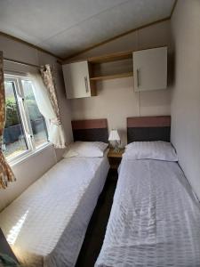 two beds in a small room with a window at The Robin's Nest in Fochabers