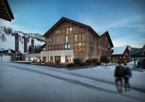 a person walking in front of a large wooden building at Gorfion Familienhotel in Malbun