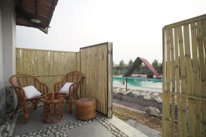a patio with two chairs and a swimming pool at Mud & Meadows- A Satvik Farmstay, Jamshedpur in Jamshedpur