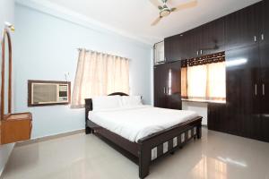 a bedroom with a bed with white sheets and a window at Sri Padam HomeStay in Tirupati