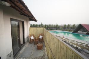 a balcony with two chairs and a swimming pool at Mud & Meadows- A Satvik Farmstay, Jamshedpur in Jamshedpur