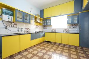 a yellow kitchen with yellow cabinets and a tile floor at Sri Padam HomeStay in Tirupati