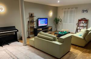 a living room with a couch and a piano at Ô Sens Jacuzzi et Massages in Challans