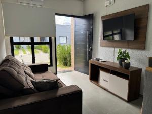 a living room with a couch and a flat screen tv at Condomínio Noruega - casas 2 dormitórios in Jaguarão