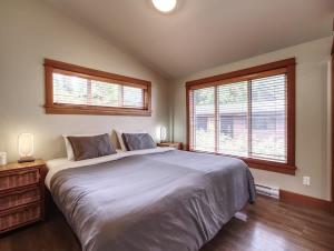 a bedroom with a large bed and two windows at Going Coastal ABC - Oceanfront - Pet Friendly in Port Renfrew