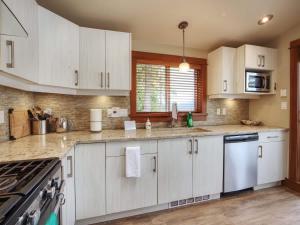 a kitchen with white cabinets and a stove top oven at Going Coastal ABC - Oceanfront - Pet Friendly in Port Renfrew