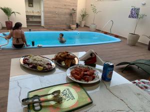 a table with food in front of a swimming pool at Pousada Recanto Populina in Populina
