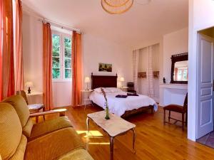 a living room with a bed and a couch at La Demeure des Fleurs in Caillavet