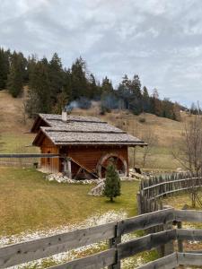 a wooden cabin in a field next to a fence at Molin in Vigo di Fassa +15 photos