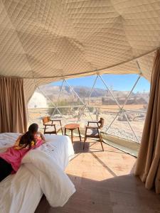 a little girl laying on a bed in a tent at Jabal shams domes in Sa‘ab Banī Khamīs