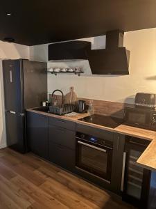 a kitchen with black cabinets and a black refrigerator at Suite romantique avec jaccuzzi - proche des lacs - La secrète room in La Mure