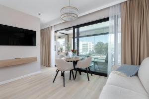 a living room with a table and chairs and a large window at Baltic Infinity Garden Suite 316 - SPA & Pool Access in Międzyzdroje