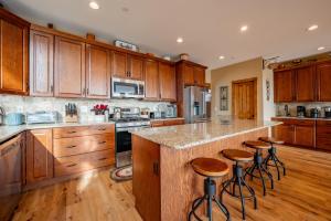 a kitchen with wooden cabinets and a island with bar stools at Bear Cliff Lodge by Railey Vacations in Friendsville