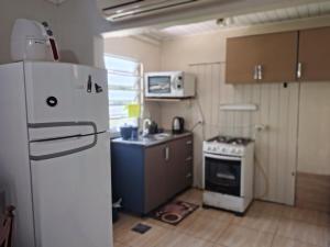 a small kitchen with a refrigerator and a stove at Apartamento sossegado e bairro tranquilo in Torres
