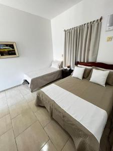a bedroom with two beds and a window at Pousada Sol Nascente in Mucuri