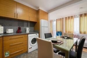 a kitchen with a dining table and a washing machine at Casa Vereda do Calhau - With barbecue in Campanário +15 photos