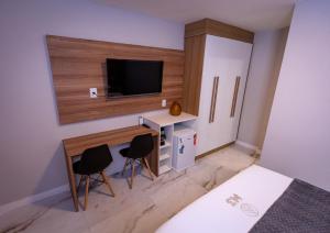 a bedroom with a desk with a tv and two chairs at M3 Studio Hotel in Camaçari