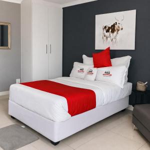 a bedroom with a large bed with red and white pillows at Kangumine Self Catering Units in Okakarara