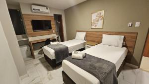 a hotel room with two beds and a television at M3 Studio Hotel in Camaçari