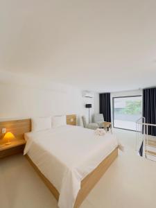 a white bedroom with a large bed and a window at Arista - Thanh My Loi in Ho Chi Minh City