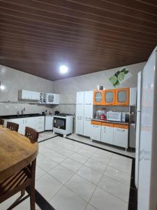 a large kitchen with white appliances and a table at Chalé Vista Pedra Azul in Domingos Martins +1 photo