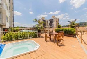 a hot tub on a patio with a table and chairs at Loft completo, garagem, piscina aquecida, jacuzzi in Porto Alegre
