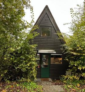 a black house with a green door and trees at Villa Edice met zwembad en restaurant in Durbuy - honden toegelaten in Durbuy