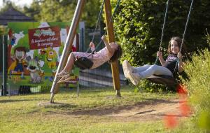 two young girls playing on swings at a park at ZEcamping 4 étoiles animaux acceptés piscine couverte in Loupiac
