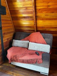 a couch with a red blanket sitting in a room at Chalé Nascer do Sol 2 in Massaranduba