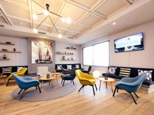 a waiting room with chairs and tables and a tv at Hotel Ambassador Zermatt in Zermatt