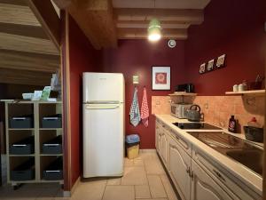 a white refrigerator in a kitchen with red walls at Lo Saunei in Laruns