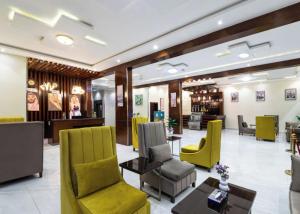 a waiting room with yellow chairs and tables at Alqasr Almutar Hotel in Abha