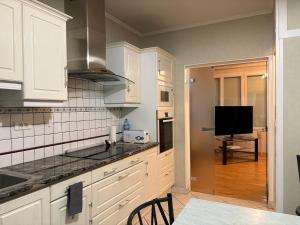 a kitchen with white cabinets and a flat screen tv at Mélusine - logement tout confort in Parthenay