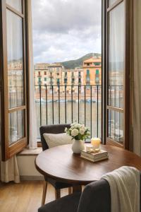 a table with a vase of flowers on it in front of a window at Bosa Exclusive Apartments "Bosa Apartments" in Bosa