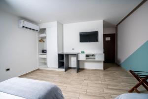 a bedroom with a desk and a tv on the wall at Hotel Puerto Pacifico Guayaquil Airport in Guayaquil