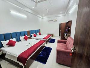 a bedroom with two beds and a red chair at Kharari Inn in Ayodhya