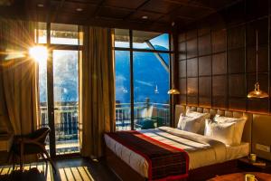 a bedroom with a bed and a large window at Hamta 270 Cliff Resort - 270 Degree Mountain View Suites, Sethan Manali in Manāli +131 photos