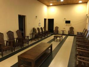 a room with wooden chairs and tables and a television at Wild Wild Holiday in Kataragama