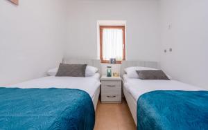 two beds in a room with white walls and blue sheets at Holiday home Atrium in Nin